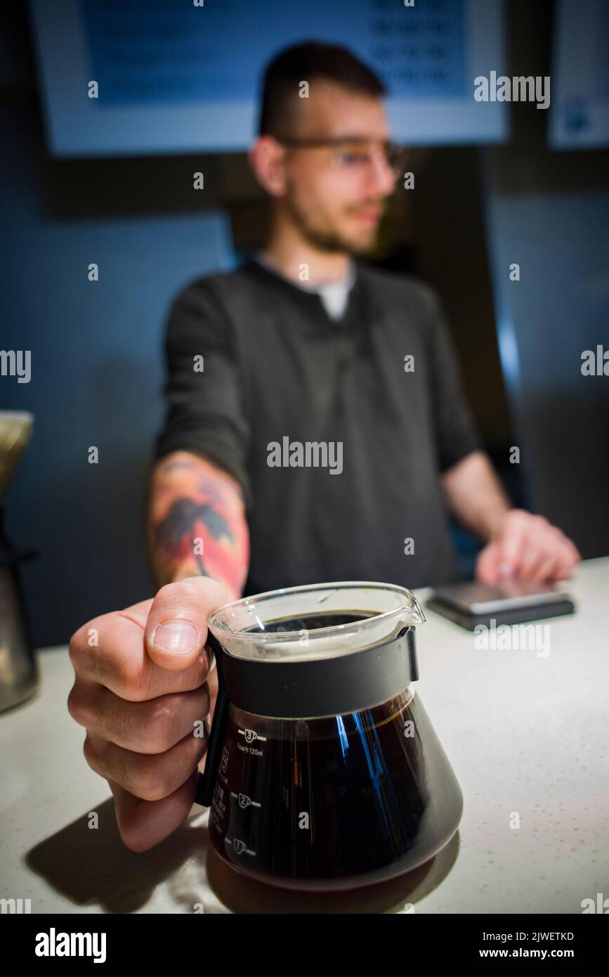 Un barista che serve il caffè in un recipiente di vetro Foto Stock