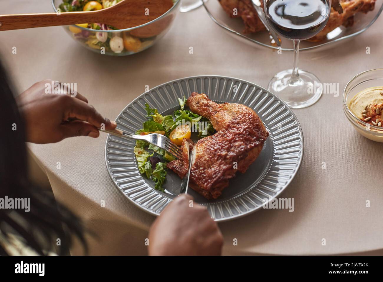 Vista ad alto angolo della donna che mangia pollo arrosto con insalata al tavolo da pranzo durante la cena Foto Stock
