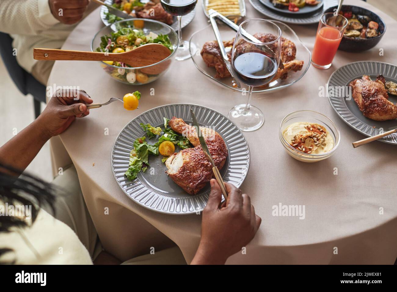 Vista dall'alto della famiglia africana che mangia pollo arrosto con insalata di verdure al tavolo da pranzo durante la cena delle vacanze Foto Stock