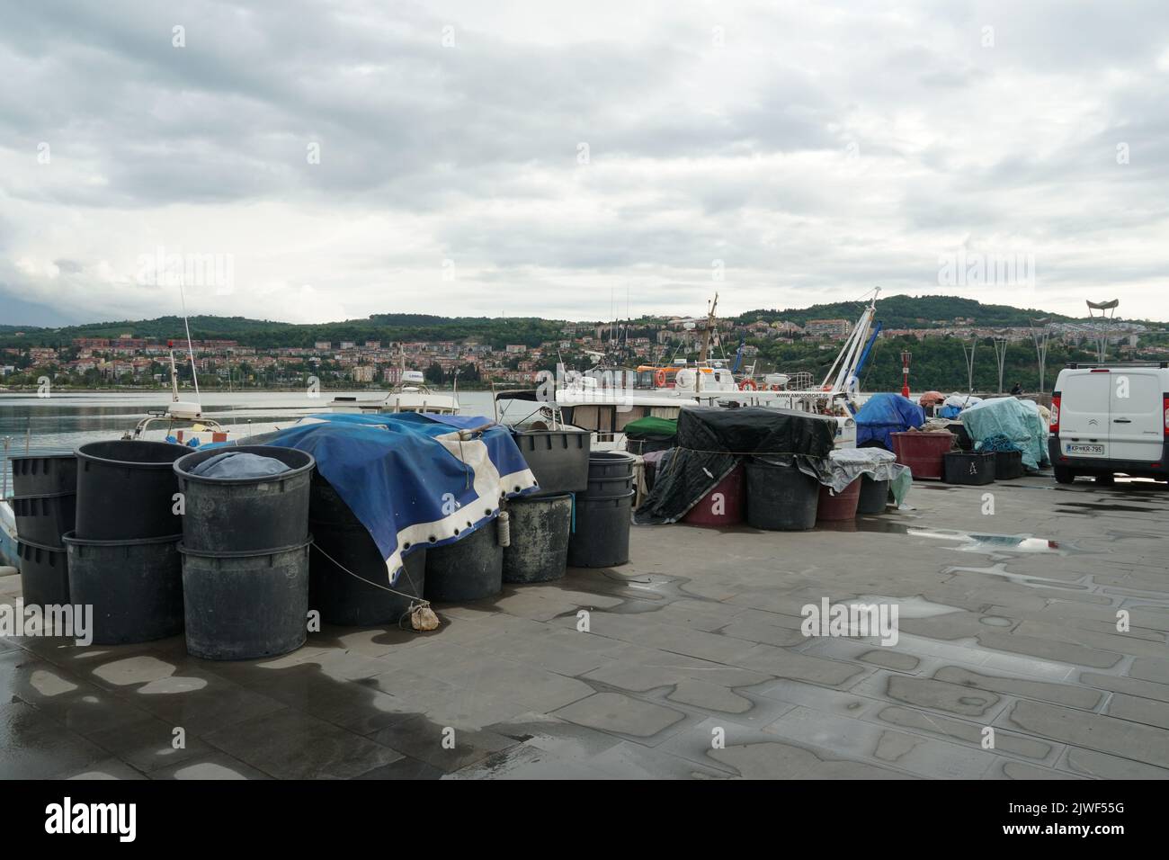 Secchi e scatole in plastica nera riempiti di reti da pesca pronti per il carico in imbarcazioni ormeggiate nel porto di pesca di Capodistria, Slovenia. Foto Stock