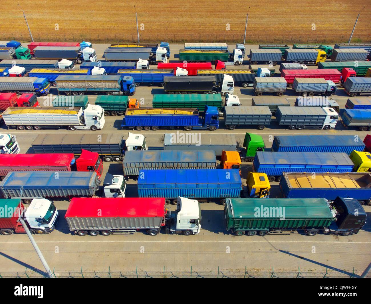 Vista aerea di camion colorati nel terminal al tramonto in estate. Vista dall'alto del centro logistico. Industria pesante. Trasporto. Trasporto merci, spedizione Foto Stock