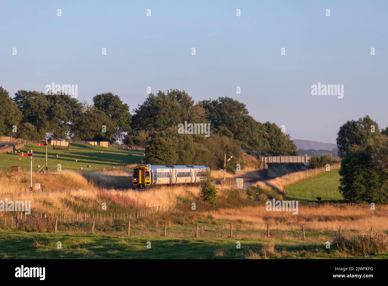 Treno a più unità diesel Northern rail classe 158 che passa i segnali del semaforo meccanico all'incrocio Settle, Yorkshire, Regno Unito Foto Stock