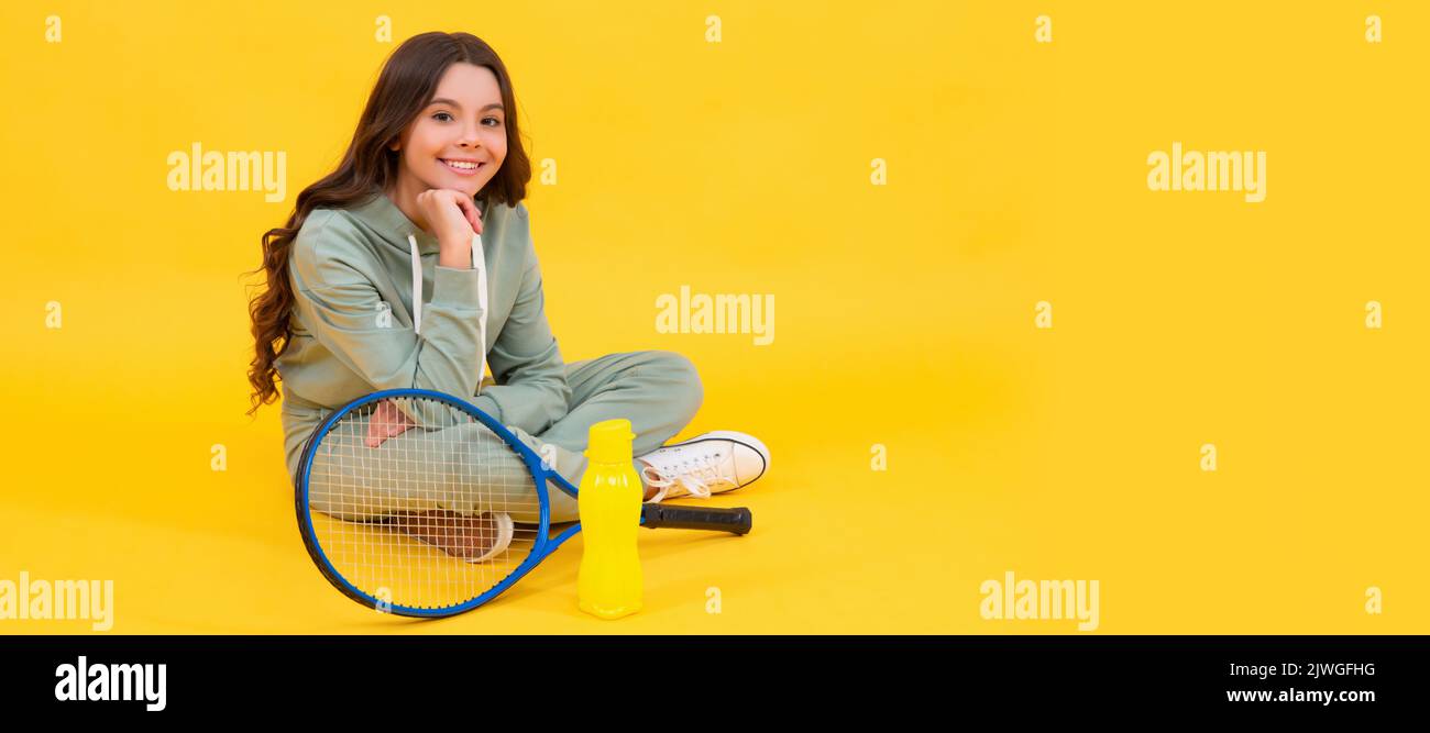 bambino allegro sedersi in abbigliamento sportivo con badminton racchetta e bottiglia d'acqua su sfondo giallo, rilassarsi. Poster orizzontale del lato bambino isolato, banner Foto Stock