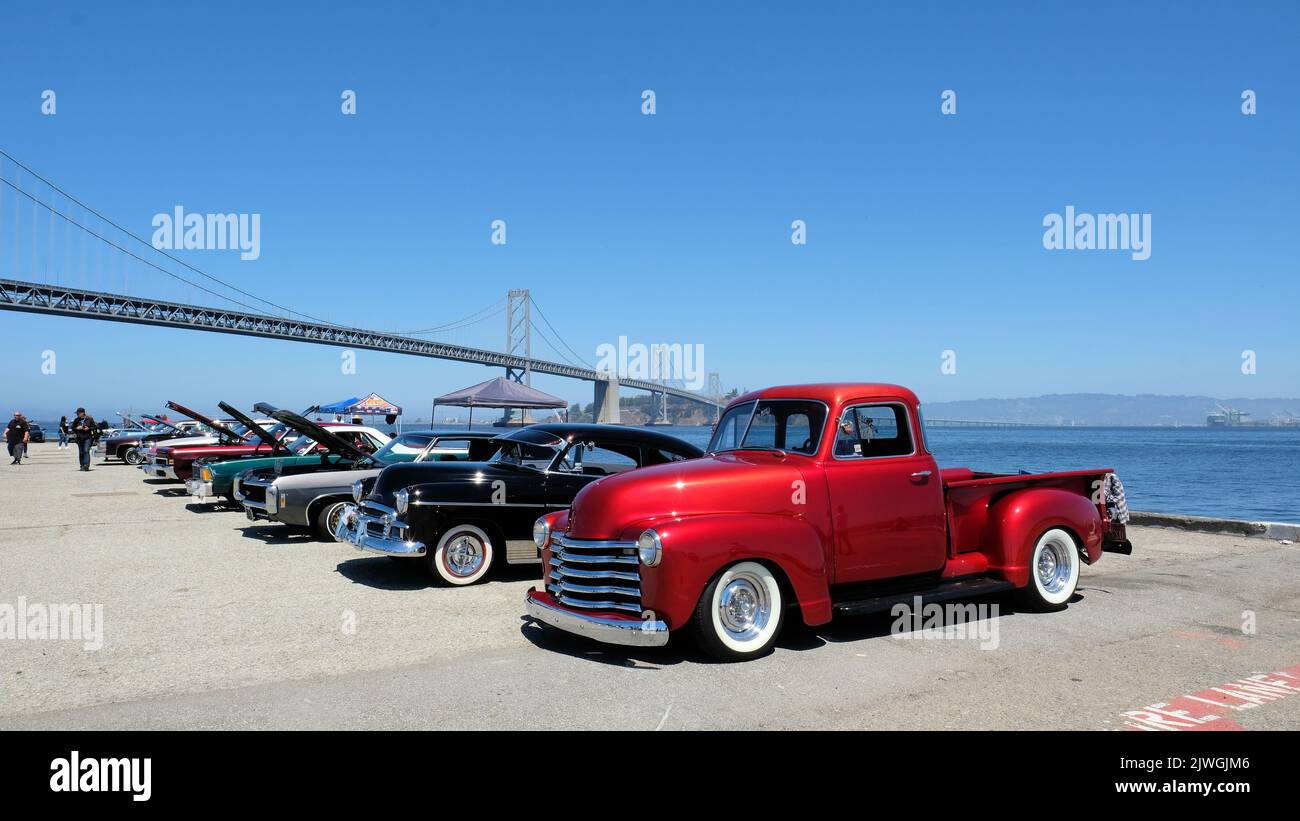 1950 Chevy Thriftmaster rosso mela caramella prelievo in uno spettacolo di auto lungo l'Embarcadero con il San Francisco Bay Bridge sullo sfondo; i più piccoli. Foto Stock