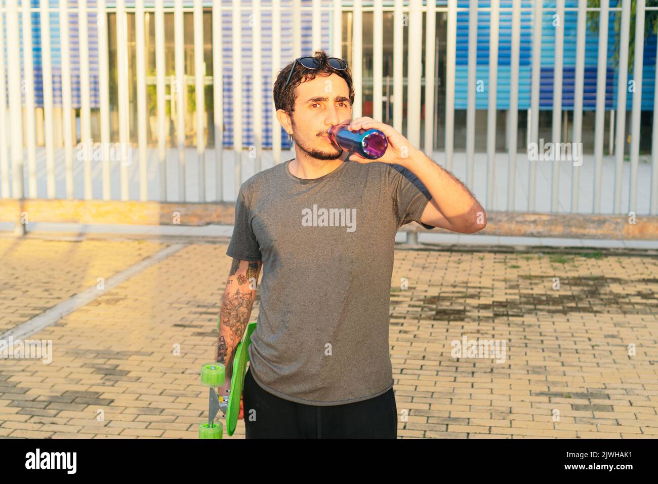 Giovane uomo che beve acqua dopo lo skateboard Foto Stock