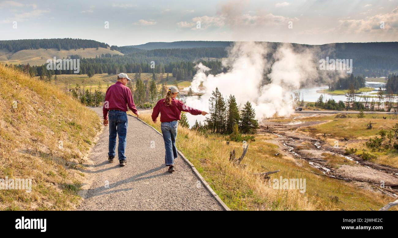 I membri della famiglia camminano su un sentiero osservando i vapori e la geologia nell'area del vulcano Mud dell'East Yellowstone National Park, Wyoming. Foto Stock