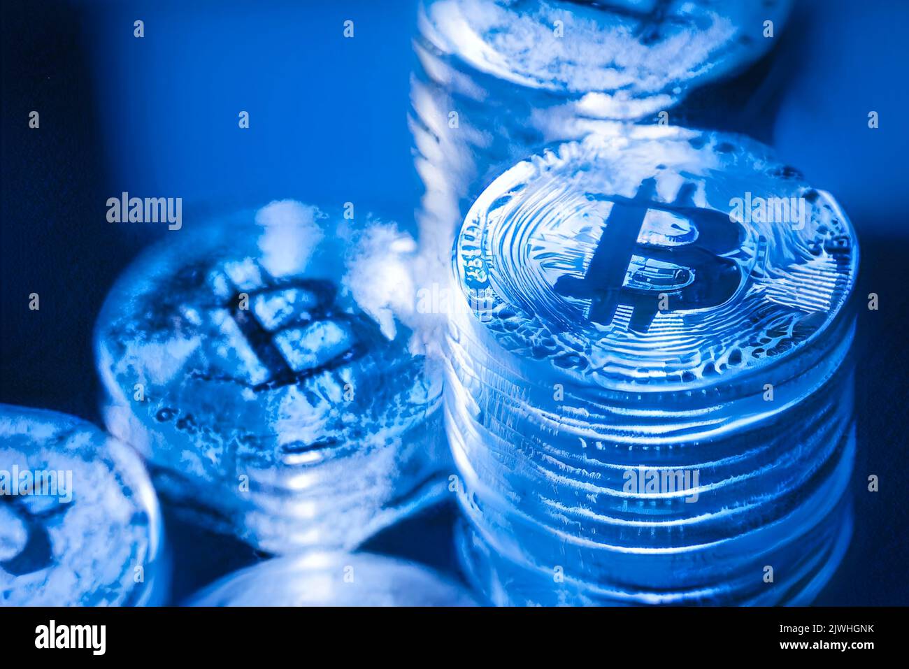 Concetto per Crypto inverno, Bitcoin in ghiaccio blu. Crollo del prezzo dei Bitcoin. Vista orizzontale dei token di criptovaluta, tra cui Bitcoin, Ethererum Ripple e Litecoin visto dall'alto su sfondo blu lucido texture Foto Stock