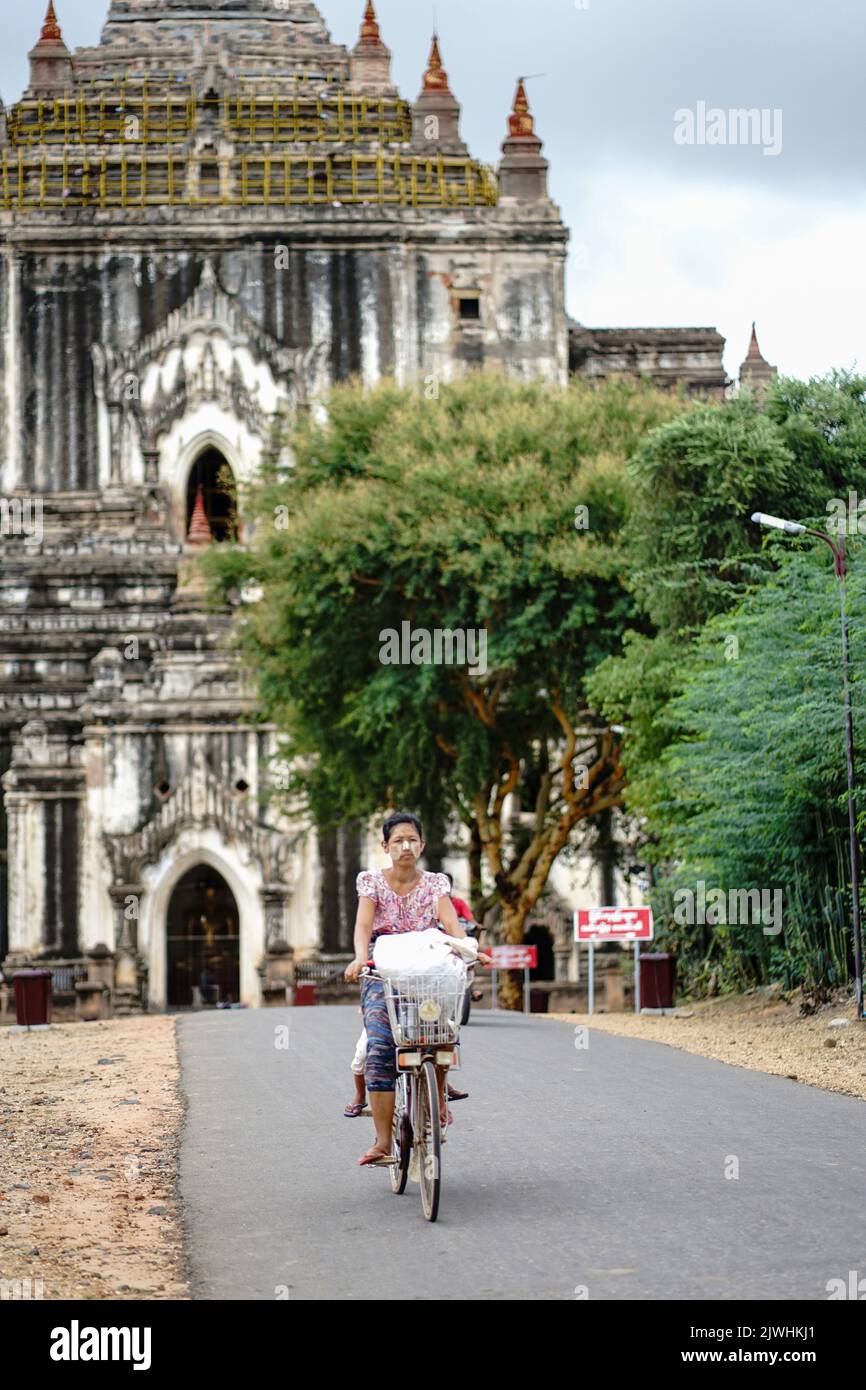 Bagan, Myanmar. 13th ago, 2022. Una donna che vende cartoline e fiori di fronte ai templi di Banag fa un giro a casa in bicicletta la sera. 'Città di mille pagode' è ciò che Bagan è chiamato. Il sito patrimonio dell'umanità è considerato uno dei più importanti siti di templi in tutto il sud-est asiatico. Per molti in Myanmar, il turismo era la principale fonte di reddito. Dopo il colpo di stato militare, nessuno viene più - e la disperazione è grande. (A dpa: Pagode orfane a Bagan: Myanmar e la fine del sogno turistico) Credit: Sai Nyi Phyu/-/dpa/Alamy Live News Foto Stock