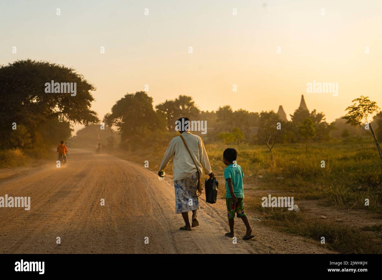 Bagan, Myanmar. 13th ago, 2022. Una madre e suo figlio camminano lungo una strada deserta a Bagan. 'Città di mille pagode' è ciò che Bagan è chiamato. Il sito patrimonio dell'umanità è considerato uno dei più importanti siti di templi in tutto il sud-est asiatico. Per molti in Myanmar, il turismo era la principale fonte di reddito. Dopo il colpo di stato militare, nessuno viene più - e la disperazione è grande. (A dpa: Pagode orfane a Bagan: Myanmar e la fine del sogno turistico) Credit: Sai Nyi Phyu/-/dpa/Alamy Live News Foto Stock