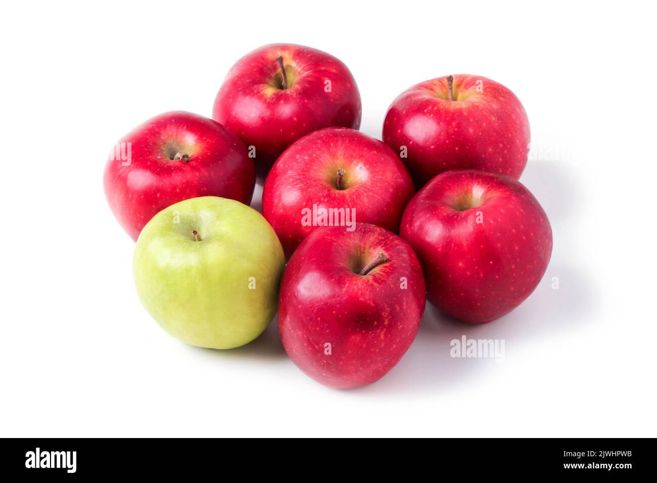 Una mela verde tra quelle rosse isolate su bianco Foto Stock