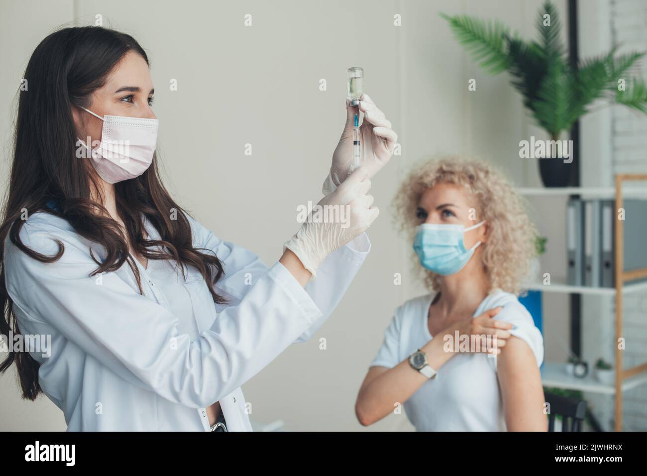 Infermiera caucasica nei guanti che estrae il liquido dalla siringa per l'iniezione. Assistenza sanitaria, medicina, farmacia e vaccinazione. Ospedale o clinica sanitaria. Covid Foto Stock