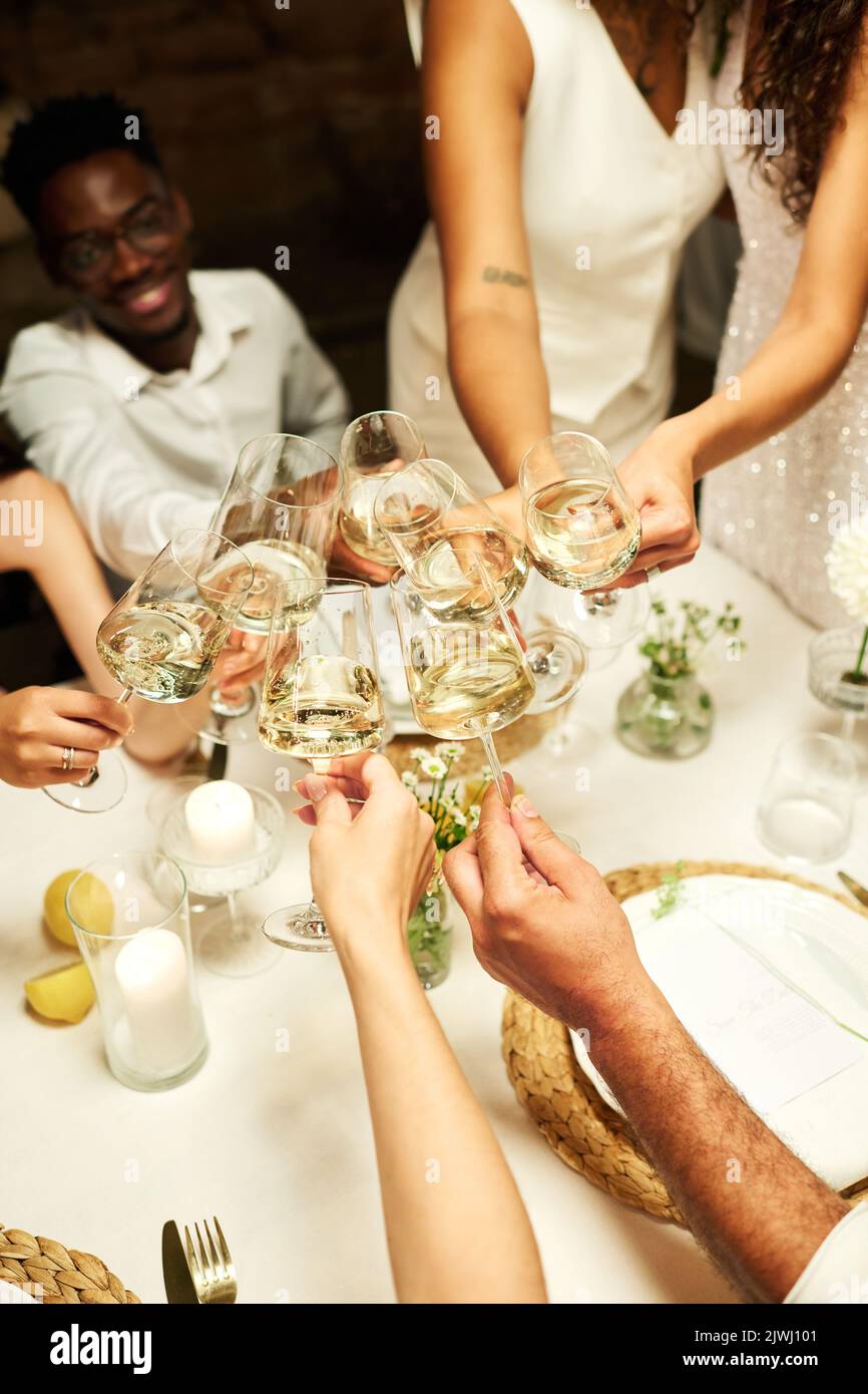 Sopra l'angolo di mani di ospiti di nozze riuniti dal tavolo festivo servito nel ristorante brinda con champagne per gli sposi novelli Foto Stock