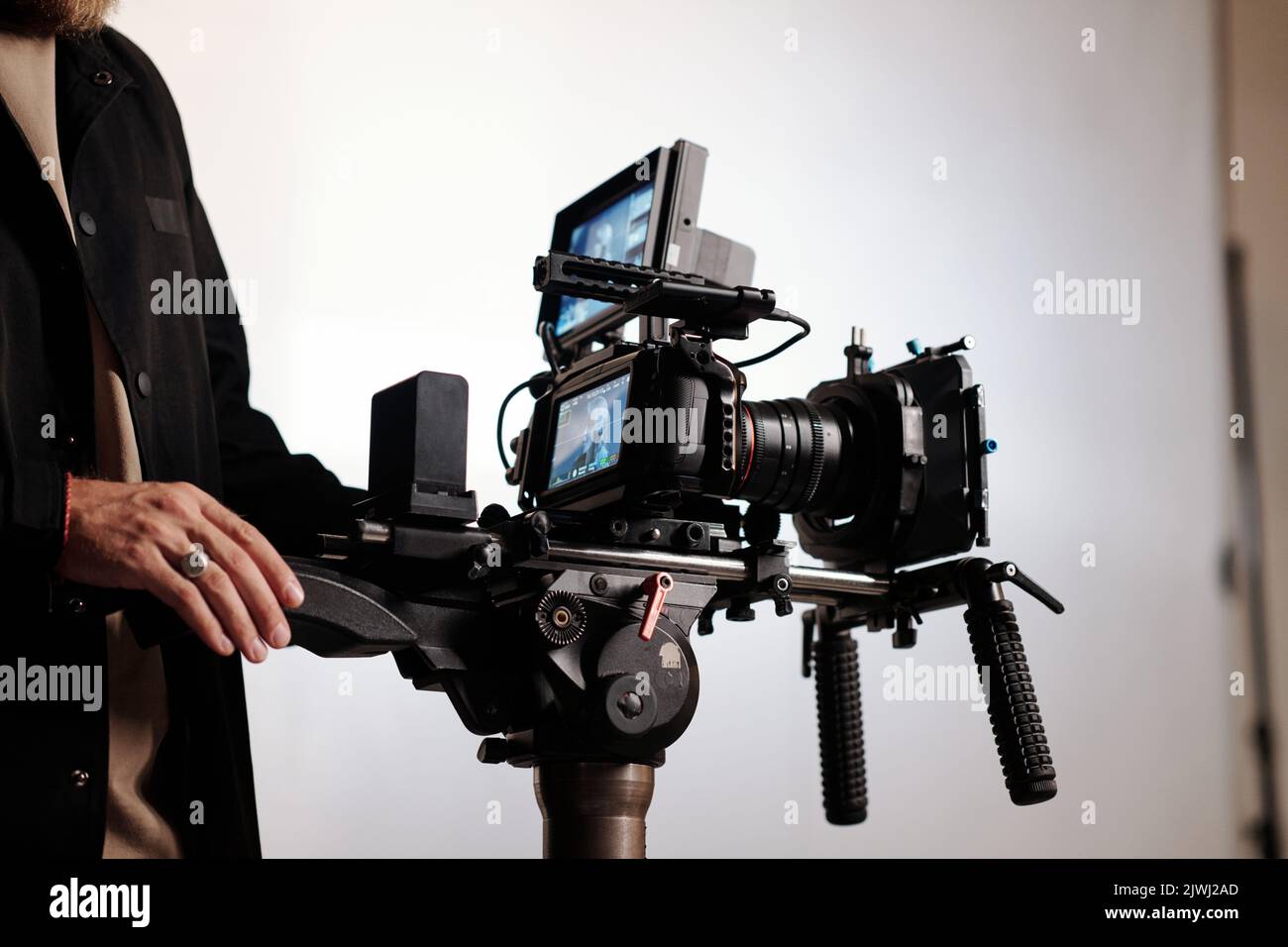 Primo piano del cameraman o del direttore del team di tiro utilizzando stalicam mentre si è in studio e lavorando sulla creazione di spot Foto Stock