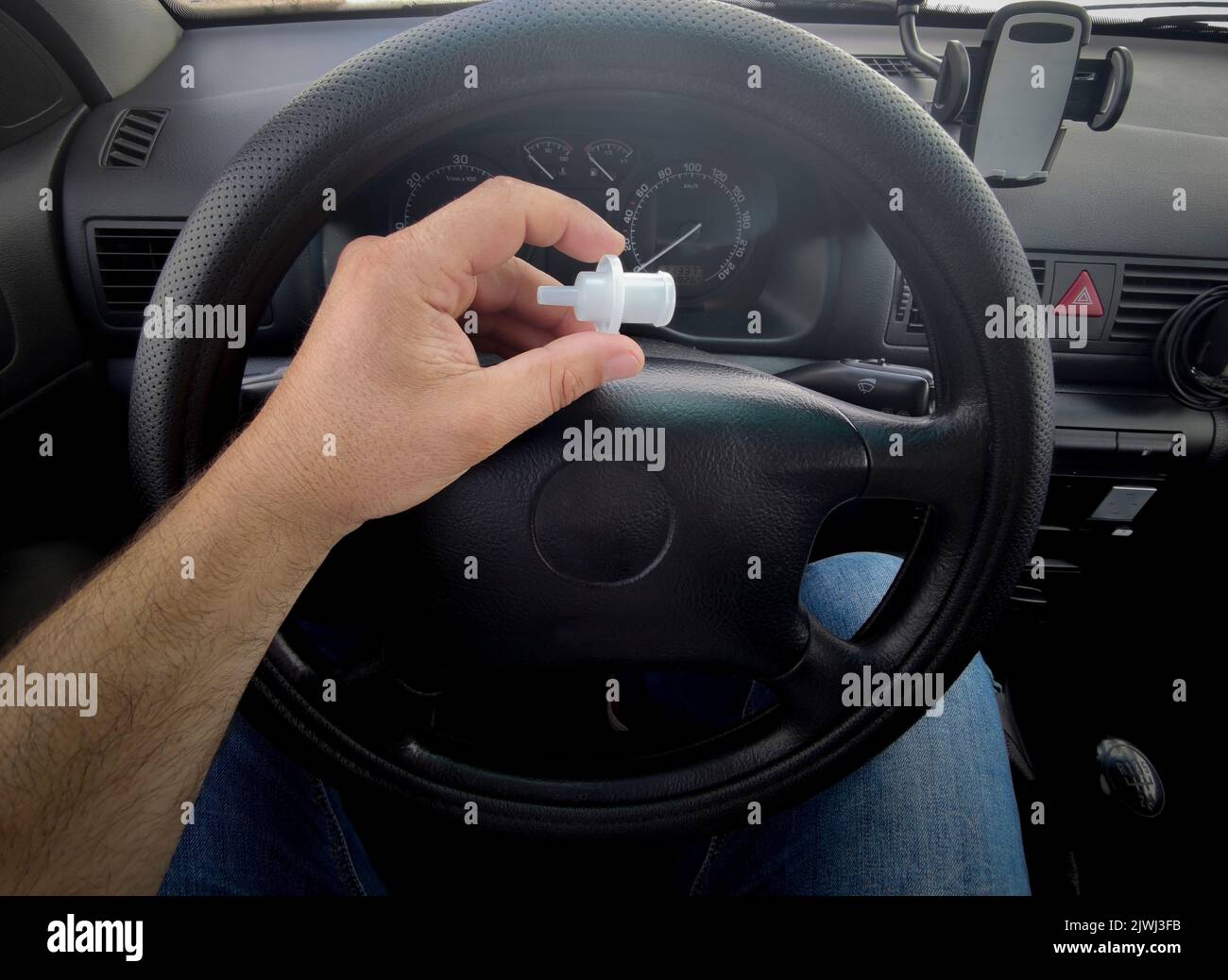 Il conducente tiene il boccaglio dell'respiratore seduto in auto. Punto di vista Foto Stock