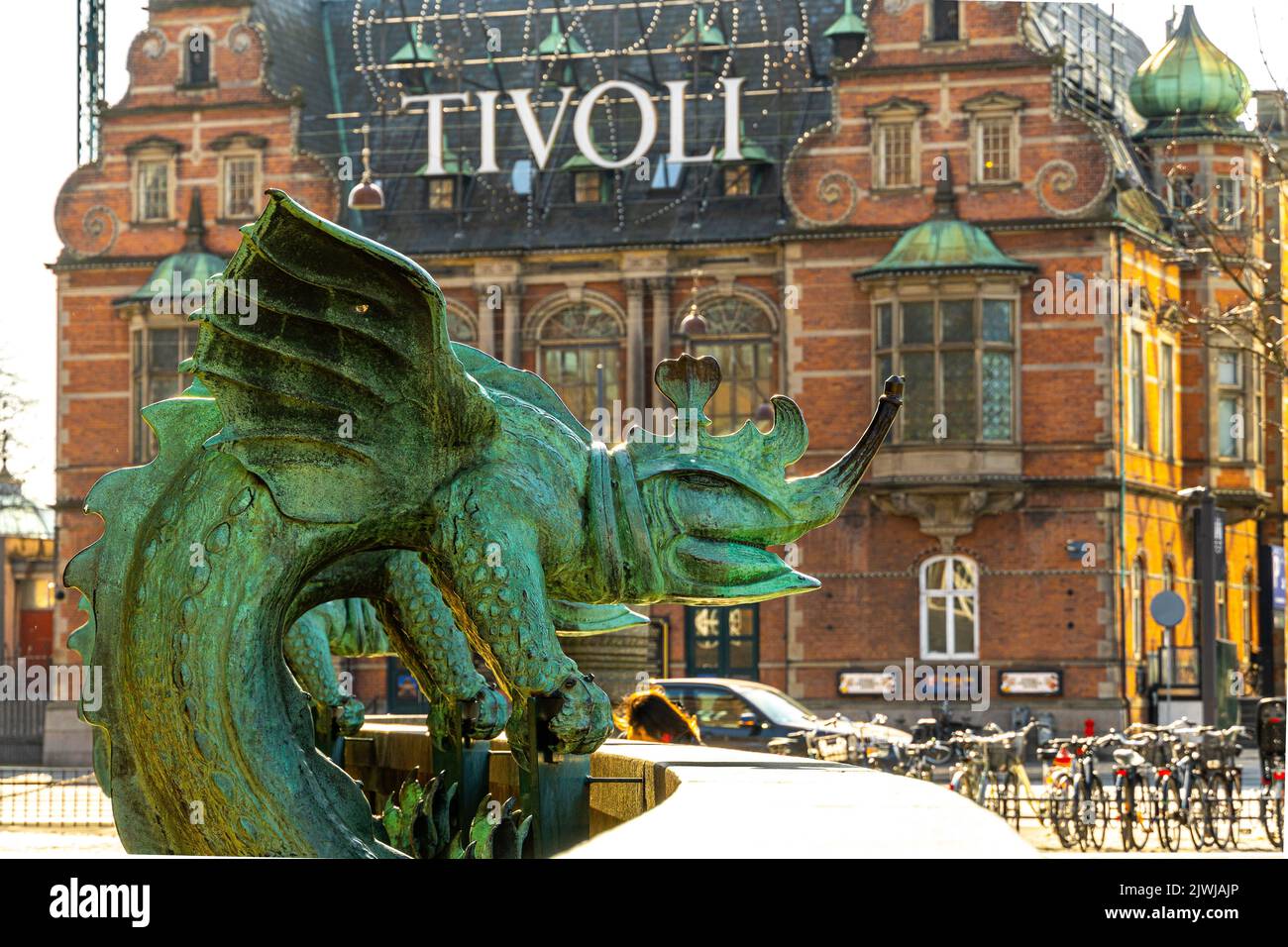 Statua di bronzo raffigurante un drago chimera con uno degli ingressi al parco divertimenti dei giardini Tivoli alle sue spalle. Copenaghen, Danimarca, Europa Foto Stock
