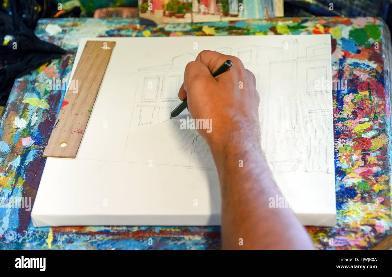 Dall'alto uomo anonimo disegno schizzo di casa su tela mentre lavora in studio creativo Foto Stock
