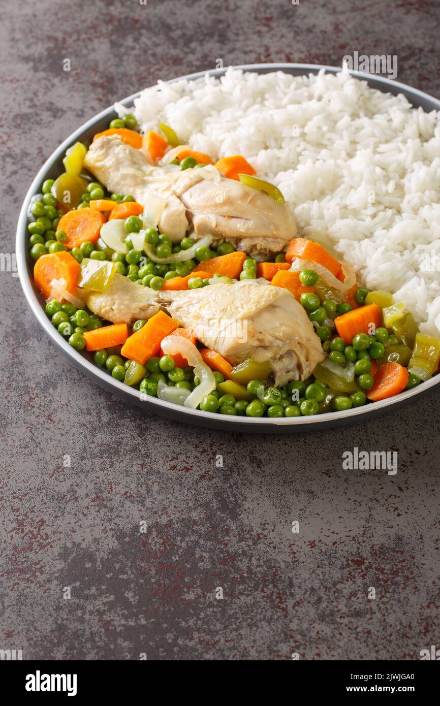 Pollo Arvejado o piselli e carote Stew di pollo è un classico cileno comfort piatto closeup nel piatto sul tavolo. Verticale Foto Stock