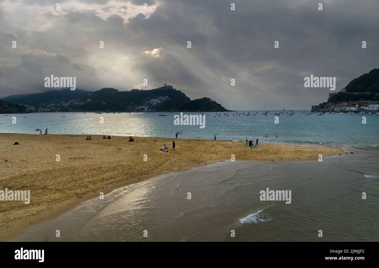 Paesaggio della spiaggia di la Concha nella città di San Sebastian, nei Paesi Baschi spagnoli, in una giornata nuvolosa al tramonto con il Monte Igueldo nel backgrou Foto Stock