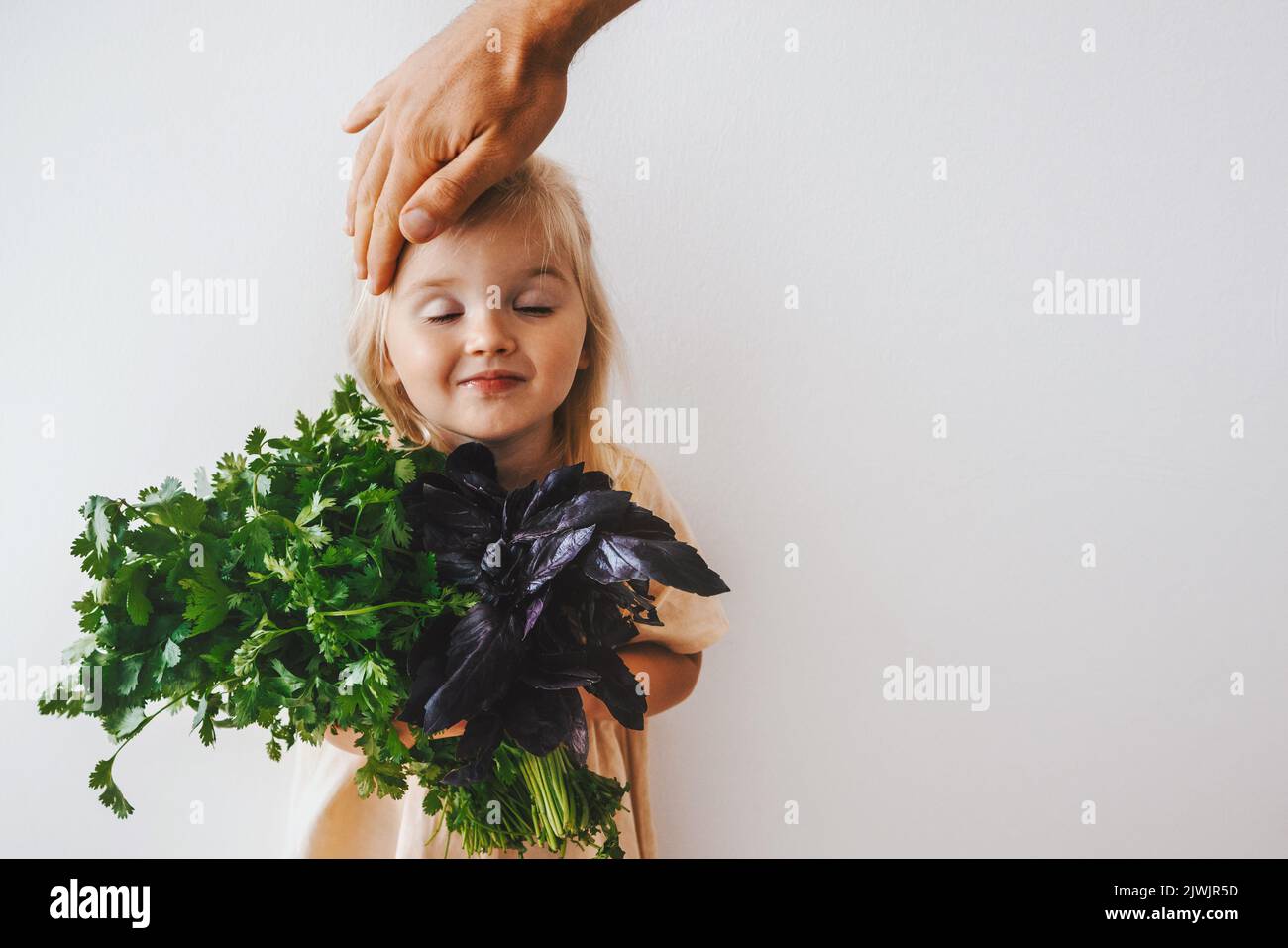 Ragazza cute bambino con coriandolo e basilico mazzo sano mangiare vegan cibo raccolto biologico fattoria giardinaggio pianta basata dieta nutrizione eco-friendly Lifest Foto Stock