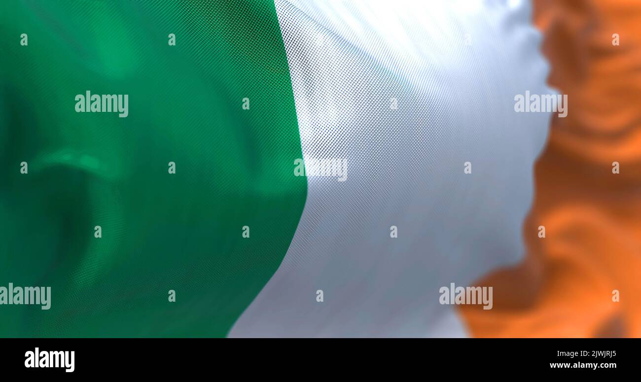 Vista ravvicinata della bandiera nazionale irlandese che sventola nel vento. L'Irlanda è un'isola nell'Oceano Atlantico settentrionale, nell'Europa nord-occidentale. Tessitura del tessuto Foto Stock