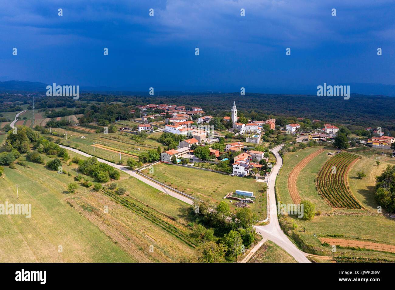 Vista aerea di uno splendido villaggio Kostanjevica na Krasu, tradizionale villaggio carsico nella zona di Komen, in una soleggiata giornata estiva, poco prima della tempesta, in Slovenia Foto Stock
