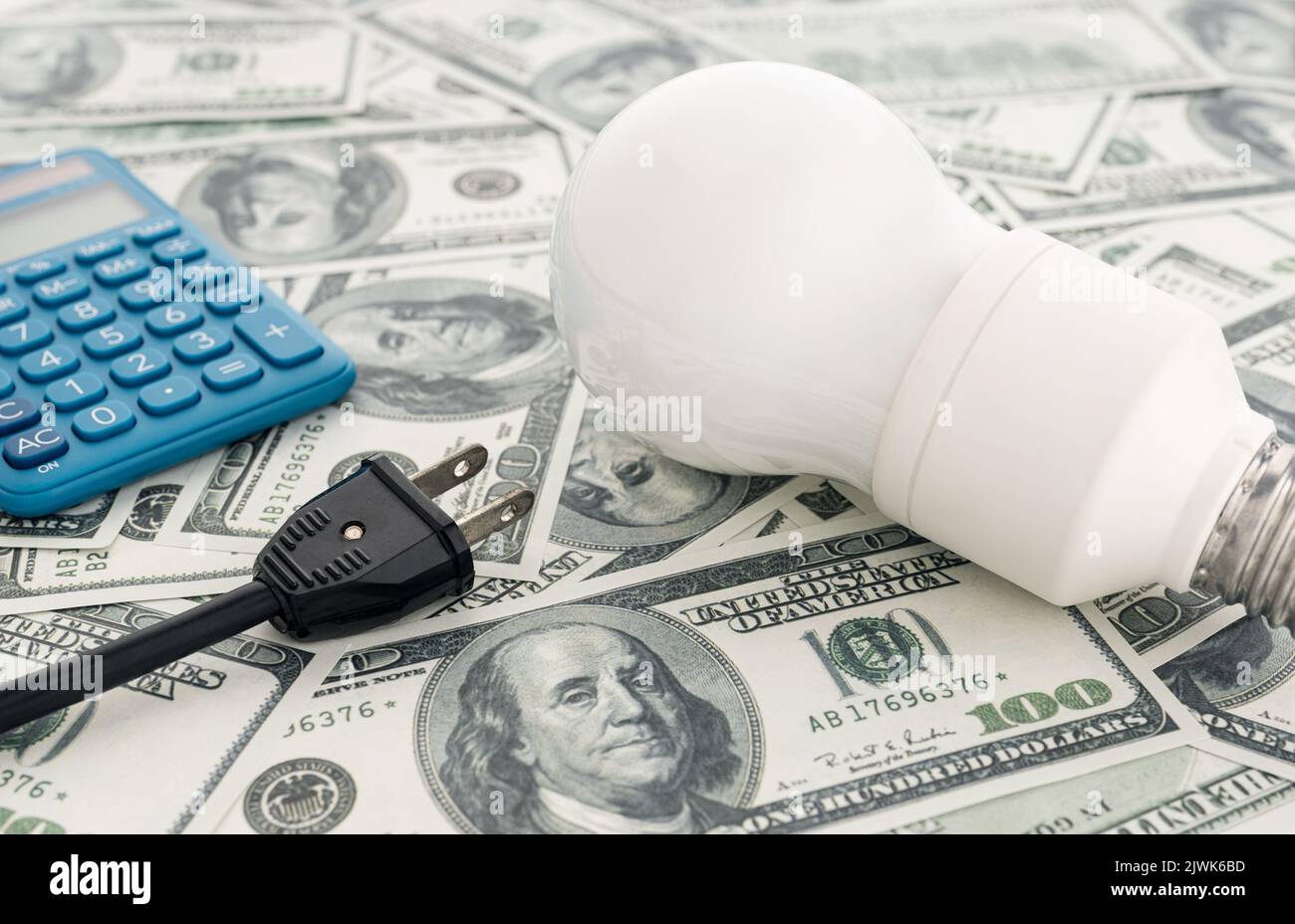 I prezzi dell'energia costano sul concetto americano. Lampadina, spina elettrica, banconote in dollari e calcolatrice Foto Stock