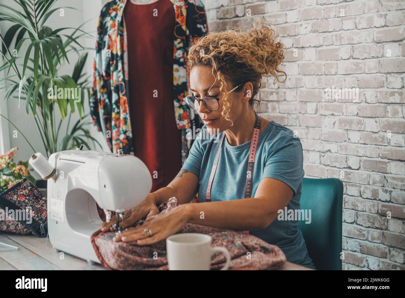 Una donna operaia a casa o in officina che utilizza e lavora con la macchina da cucire come un marinaio. La gente femminile felice del lavoratore con il commercio alternativo domestico Foto Stock