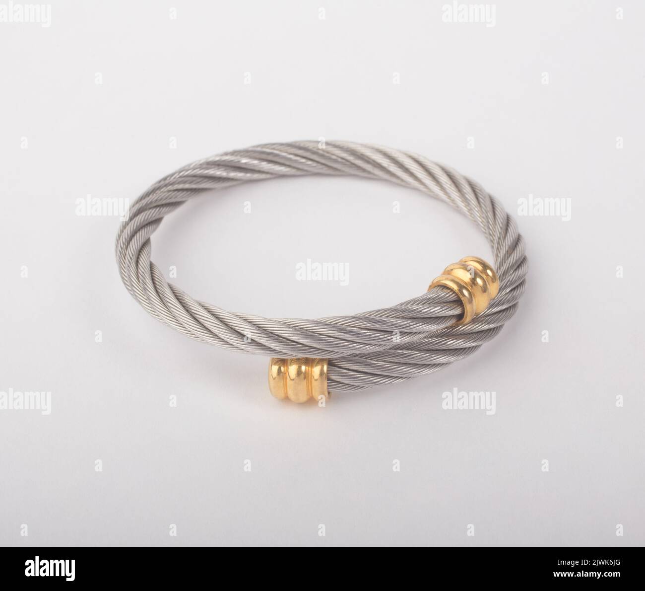 Bracciale rigido in argento a spirale decorato con isolato dorato su sfondo bianco Foto Stock
