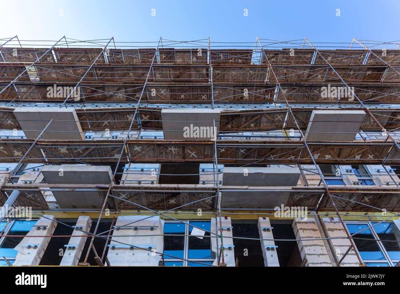 Isolamento delle pareti esterne di un edificio in costruzione. Le pareti dell'edificio in costruzione sono circondate da ponteggi per lavori Foto Stock