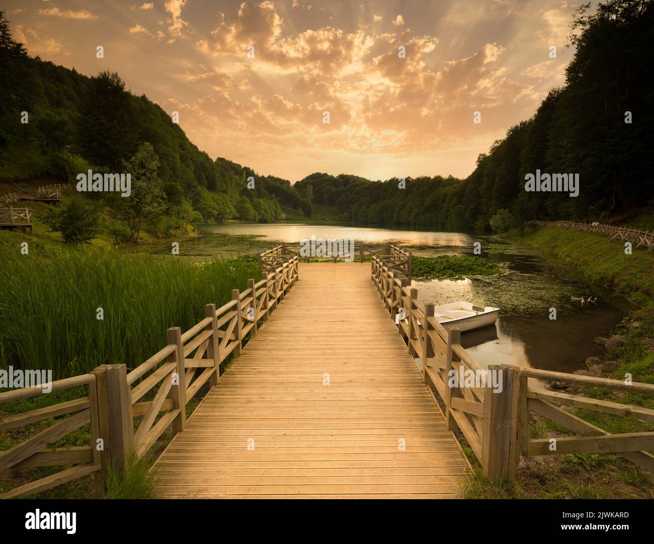 Molo del lago al tramonto. Lago calmo nella foresta. Foto Stock