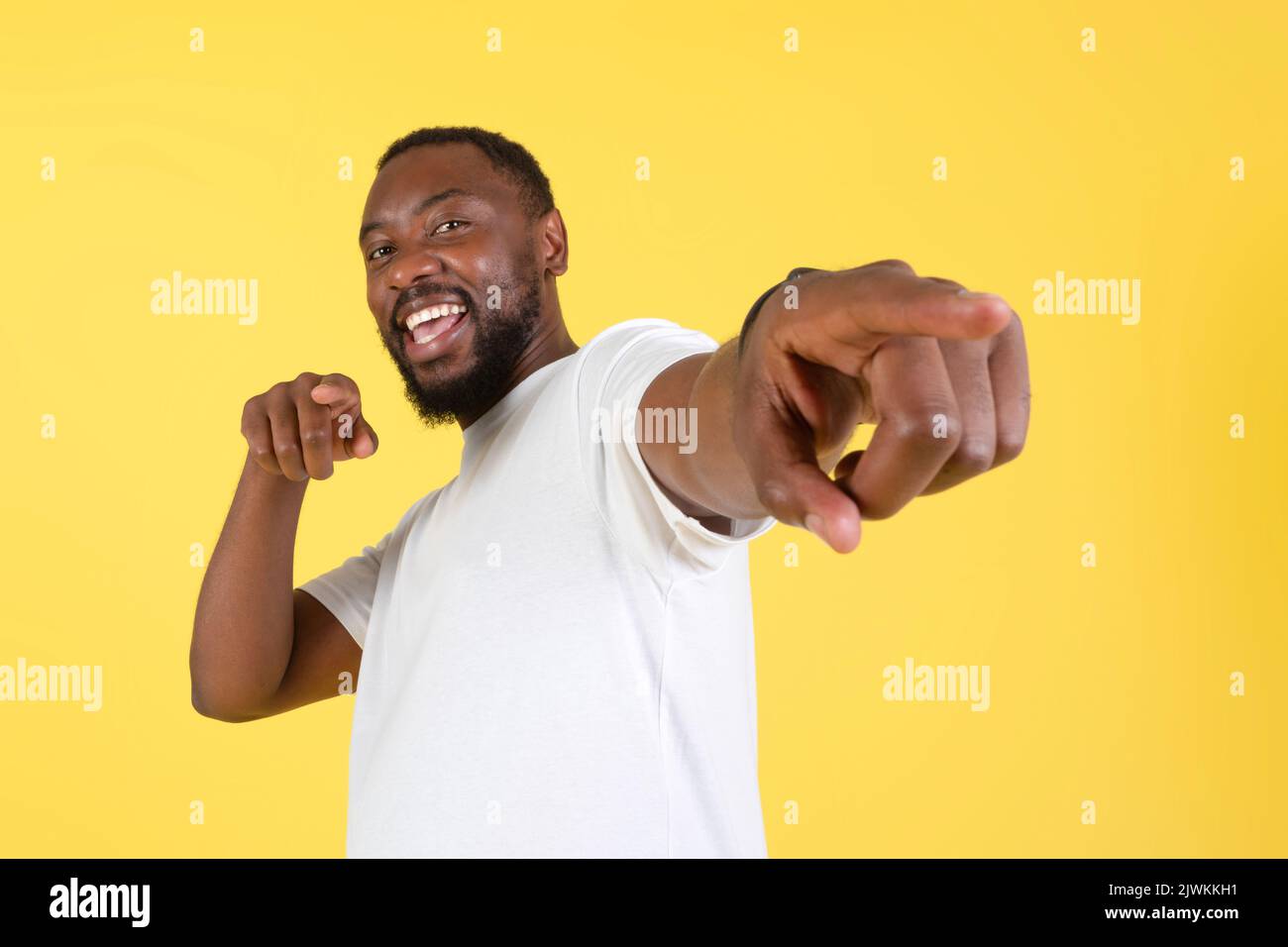 Cheerful afro americano maschio che punta le barrette che lo scelgono, sfondo giallo Foto Stock