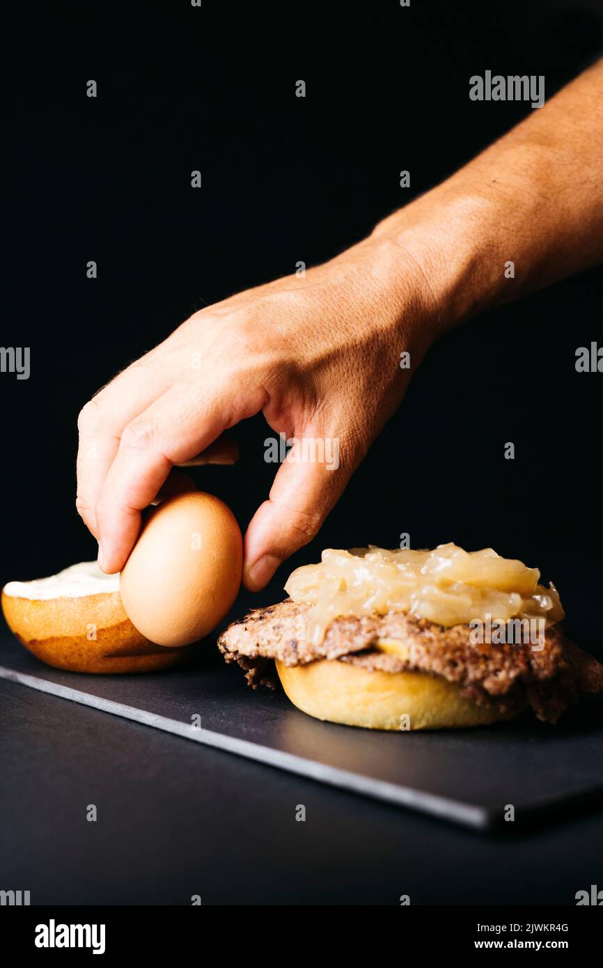 Doble smashburger con cipolla cotta e un uovo bollito su uno sfondo nero Foto Stock
