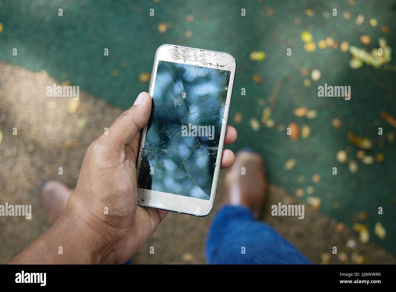 Primo piano della mano dell'uomo che tiene in mano lo smartphone rotto. Foto Stock