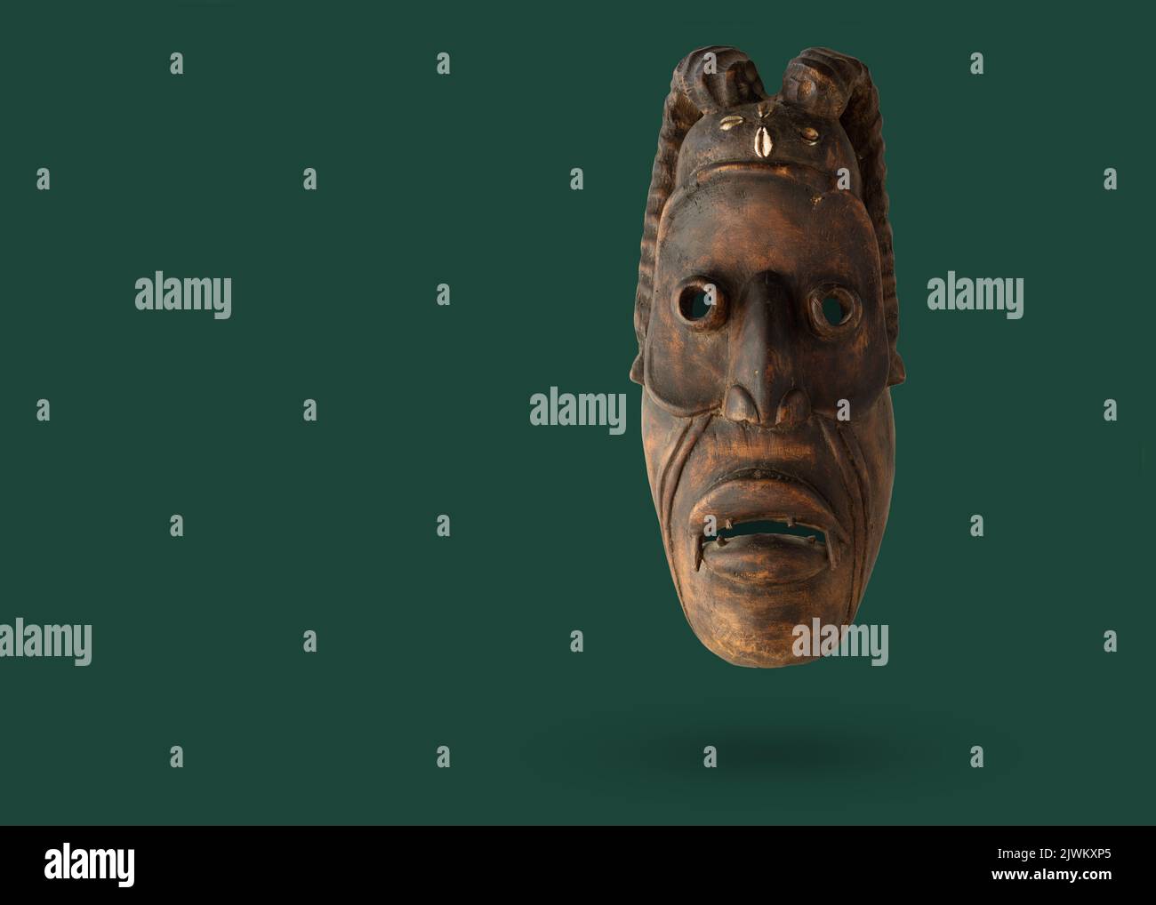 Maschera africana in legno che si levitating su uno sfondo verde. Maschere uso in rituali e cerimonie. Foto Stock