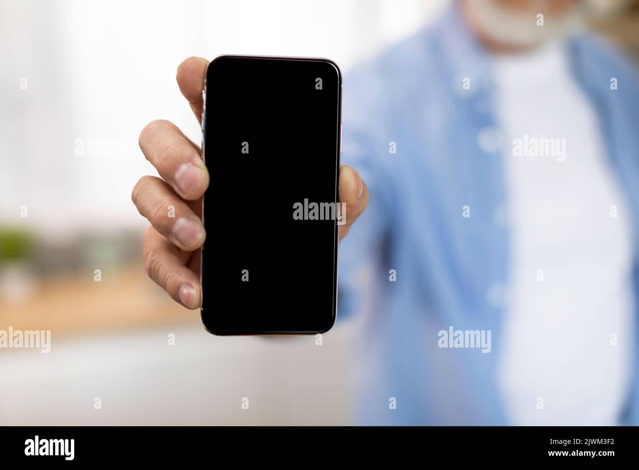Un uomo anziano irriconoscibile che tiene uno smartphone moderno con un grande schermo vuoto Foto Stock