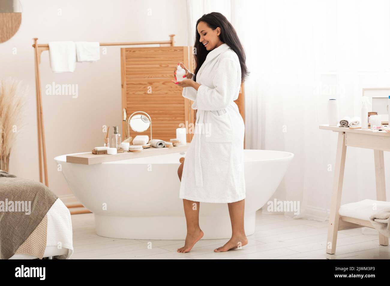 Donna nera corpo di tenuta Balm flacone idratante pelle in bagno Foto Stock