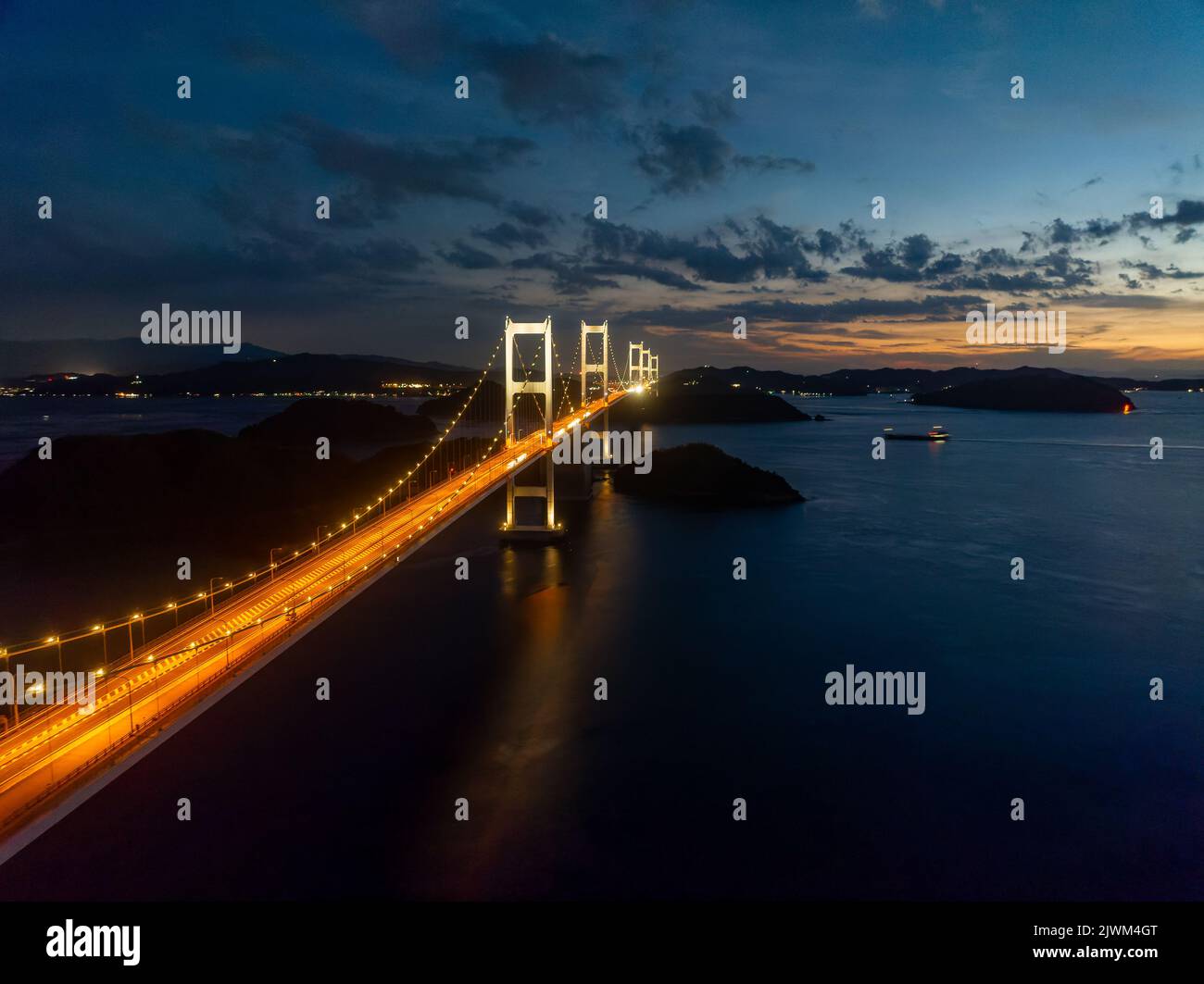 Le luci dell'auto strisciare attraverso il lungo ponte sospeso in prima serata Foto Stock