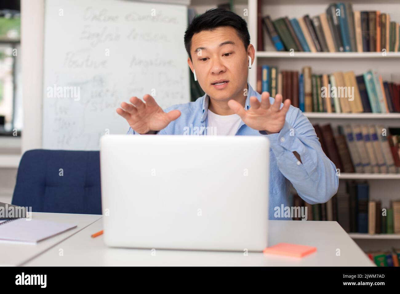 E-insegnante cinese uomo che parla con il portatile che ha lezione indoor Foto Stock