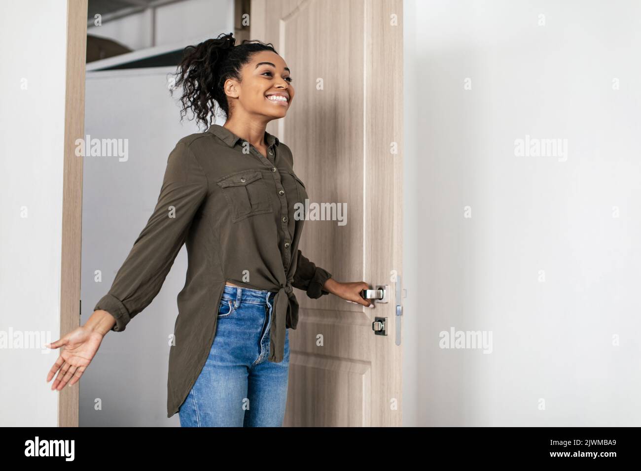 Joyful Black femmina porta di ingresso apertura entrando nuovo appartamento in affitto Foto Stock