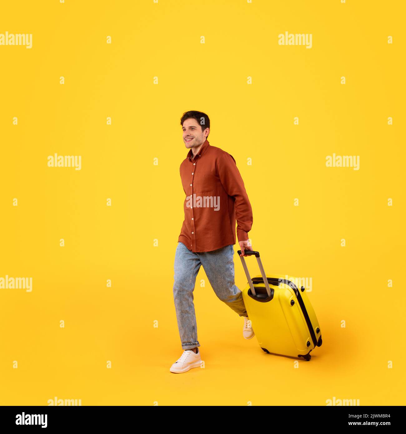 Maschio Tourist Walking con bagagli in vacanza, sfondo giallo Foto Stock