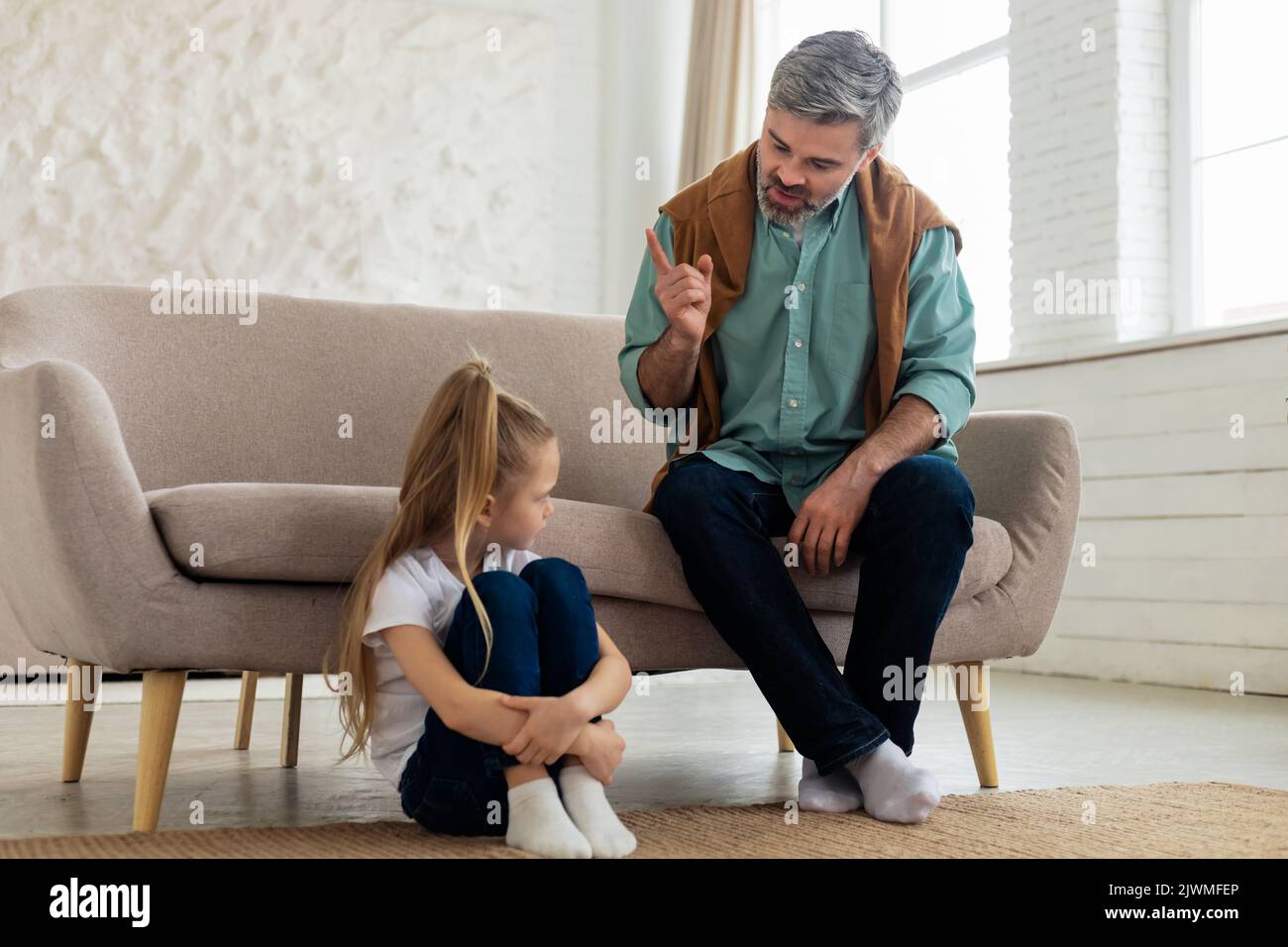 Il Padre rigoroso scolding figlia triste per il cattivo comportamento a casa Foto Stock