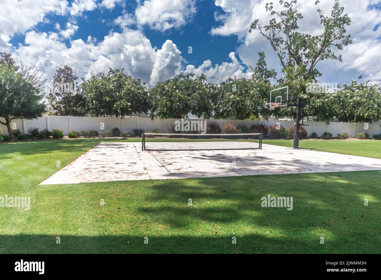 Un grande cortile con erba verde e un campo da basket che è stato fatto in un campo di pickleball casa Foto Stock