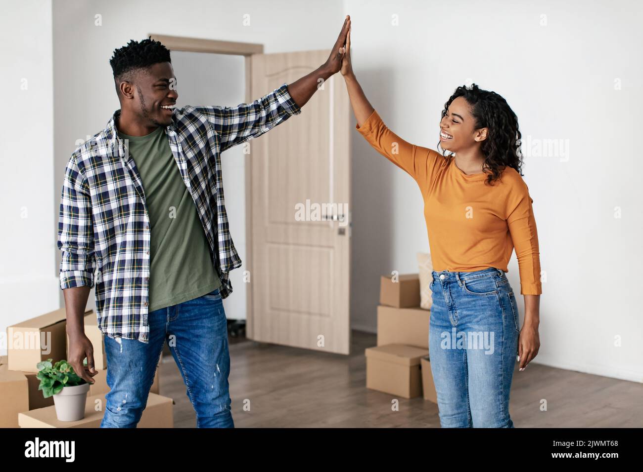 Coniugi neri che danno High Five in piedi tra scatole di cartone interno Foto Stock