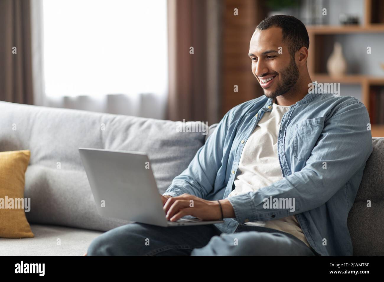 Lavoro remoto. Bel giovane giovane freelance nero che usa il notebook a casa Foto Stock