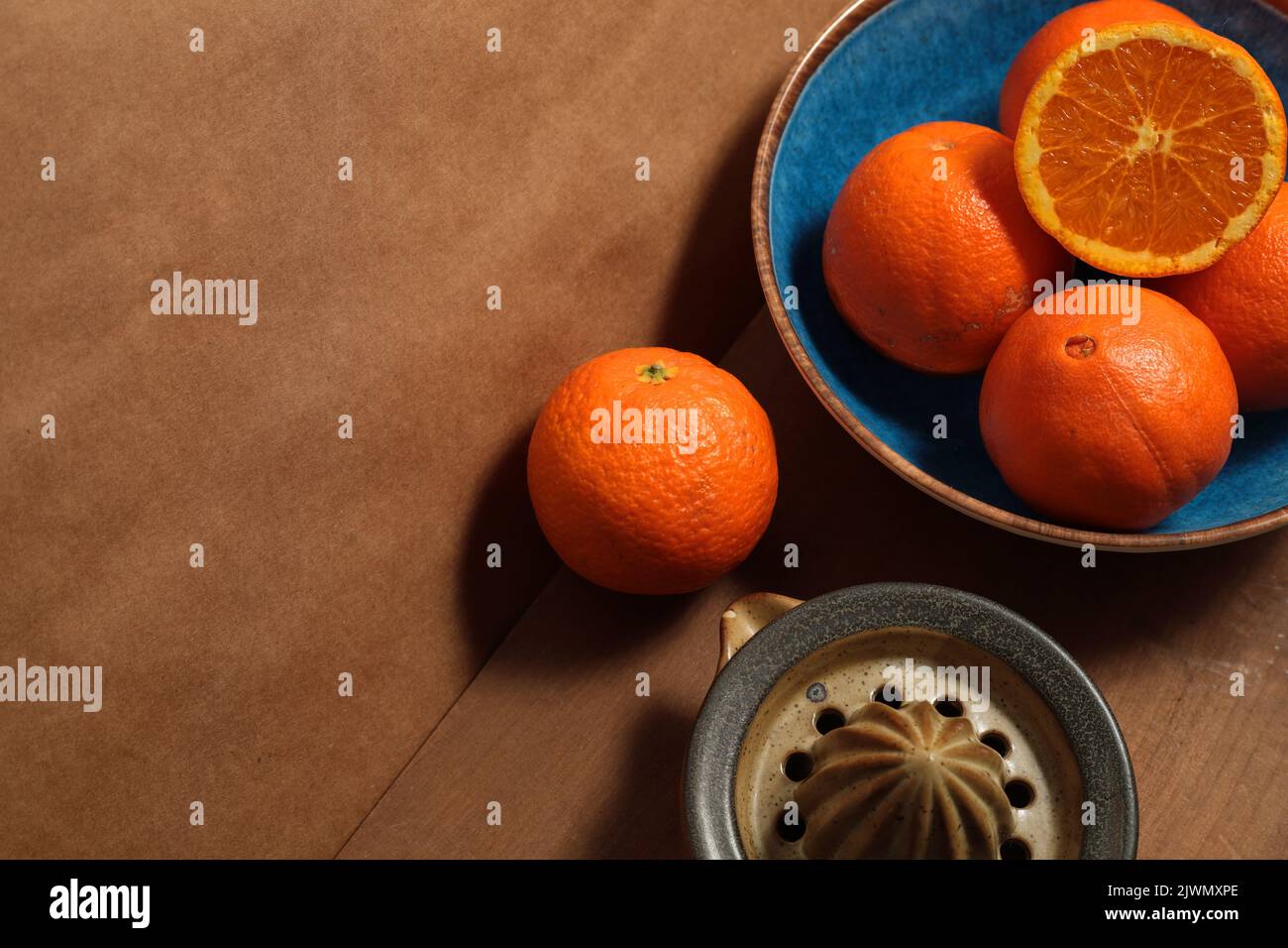 Ancora vita con arance su piatto blu su tavola di legno Foto Stock