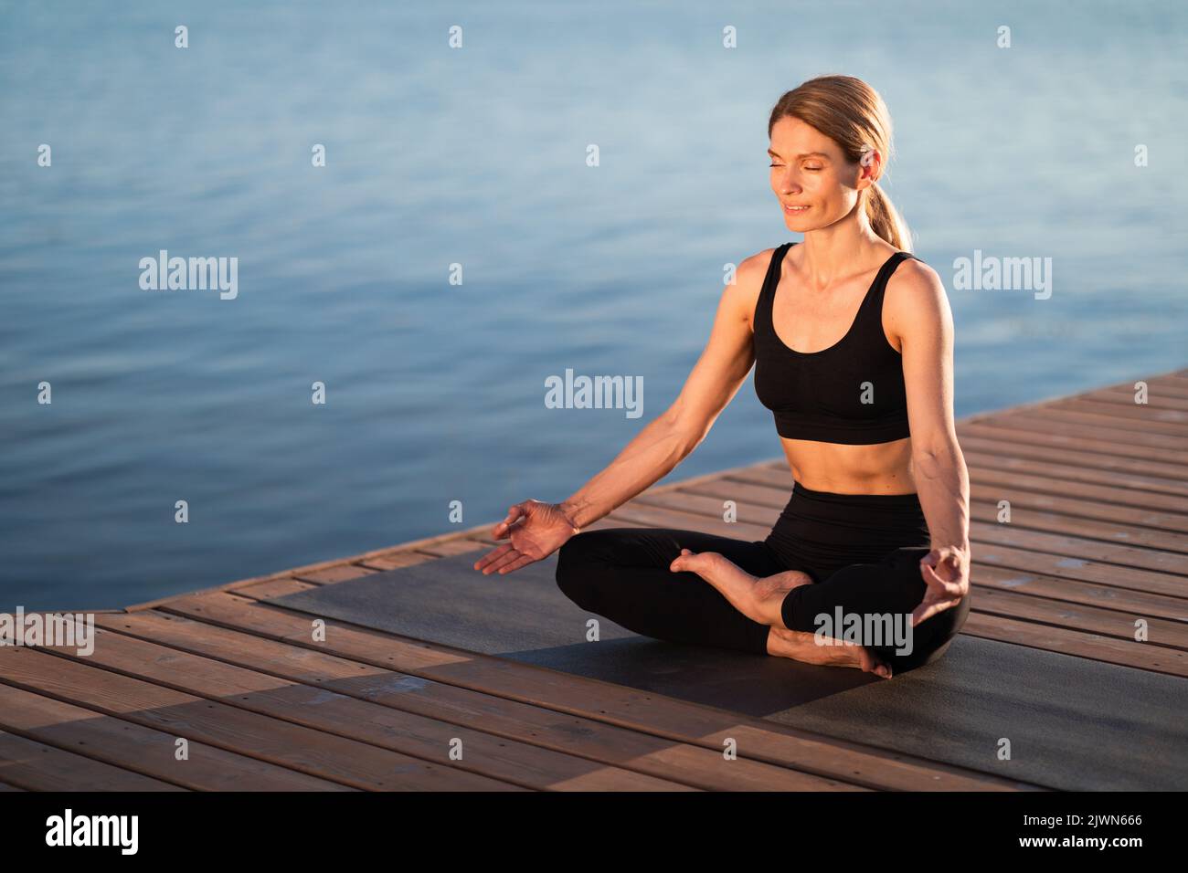 Concetto di benessere. Bella donna di mezza età in Activewear meditando all'aperto Foto Stock
