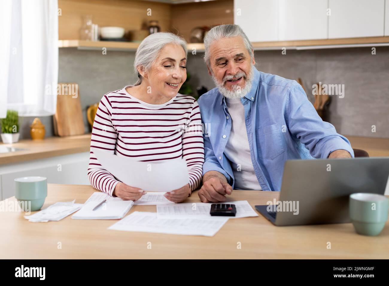Sposi anziani felici che fanno la pianificazione di preventivo della famiglia in cucina Foto Stock