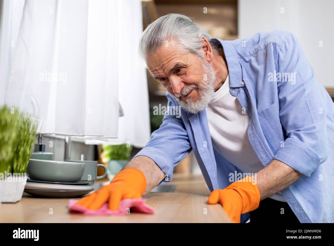 Ritratto di uomo anziano sorridente tavolo di lavaggio in cucina con Rag Foto Stock