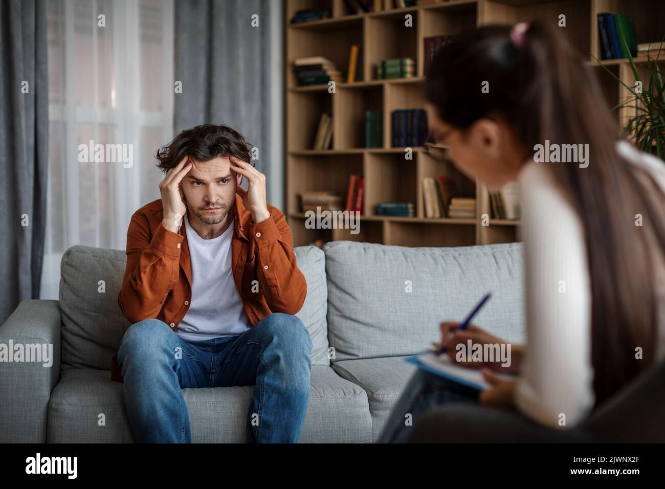 Depresso giovane paziente caucasico disperato parla con medico psicologo in ufficio Foto Stock