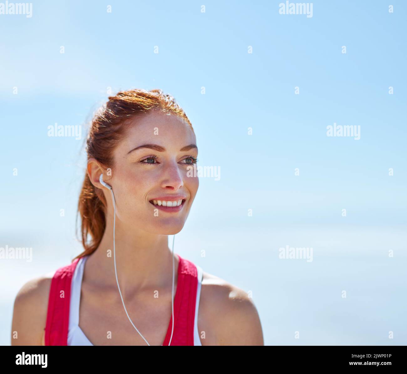 Pensare solo a un allenamento fa sorridere una giovane donna sportiva sulla spiaggia. Foto Stock